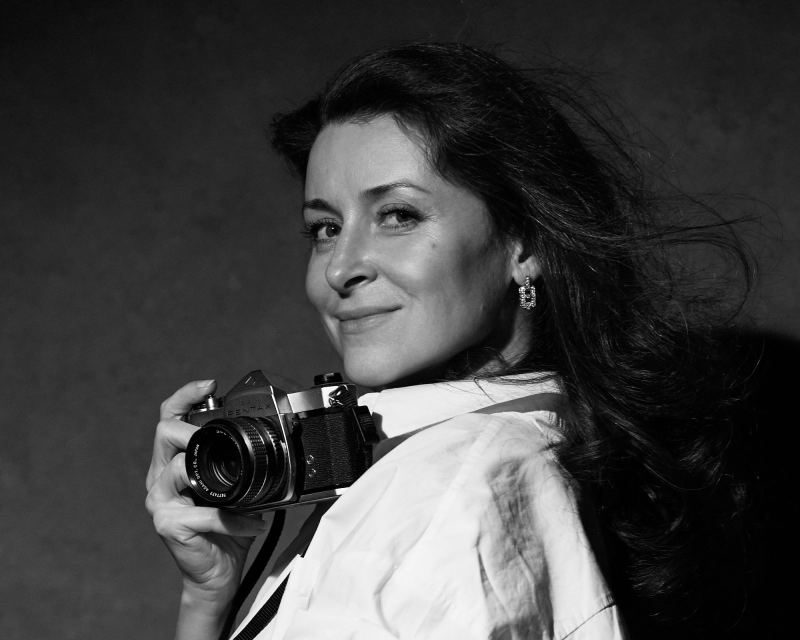 Alisia Green holding a camera, photographed in black and white