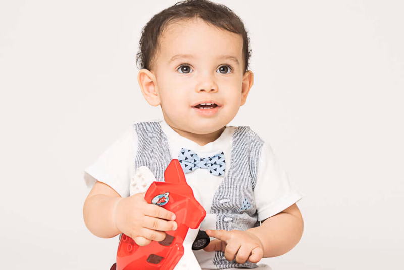a baby boy sitting on the floor holding a toy