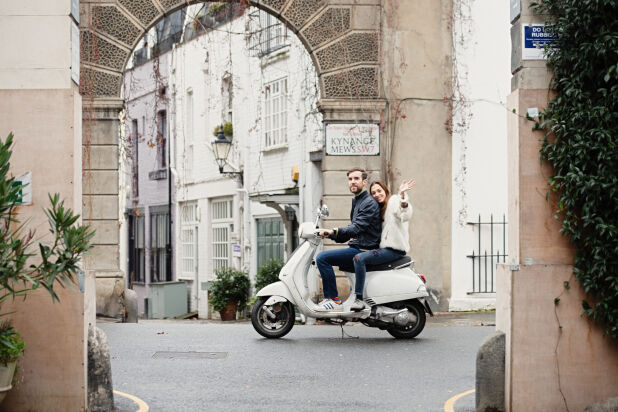 a couple riding a scooter down a street