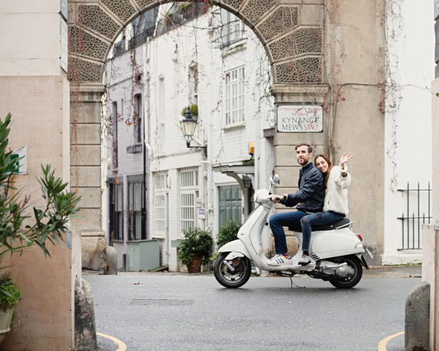 a couple riding a scooter down a street