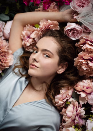 a woman laying in a bed of flowers