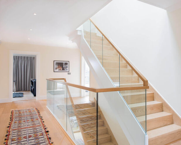 a staircase with a glass railing and a rug