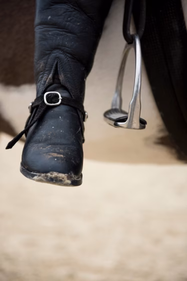 a person riding a horse with a black boot