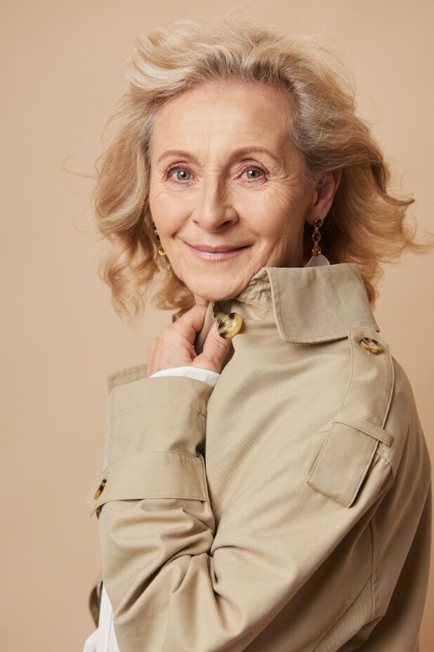 a woman with blonde hair and a tan jacket